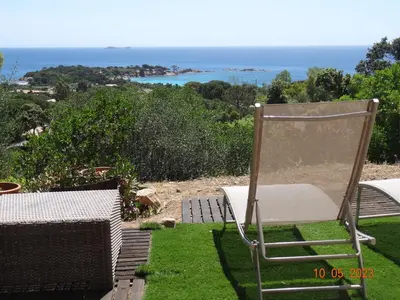 a chair sitting on the grass near the ocean at Villa indépendante 2/5 personnes - Palombaggia Vue mer magnifique Porto Vecchio in Porto-Vecchio