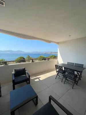 a balcony with a table and chairs and the ocean at Loc A Machja Fiurita - Vue mer in Pietrosella