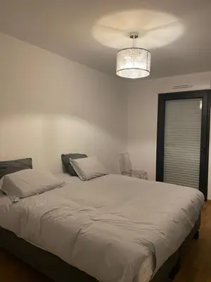 a bedroom with a large white bed with a chandelier at Loc A Machja Fiurita - Vue mer in Pietrosella