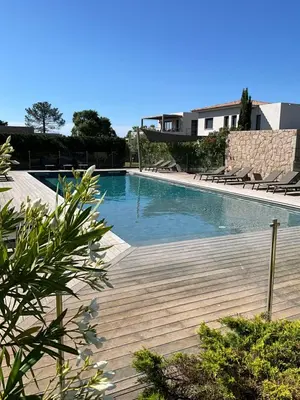 a swimming pool with chairs and a wooden deck at Villa U Sanda in Lecci