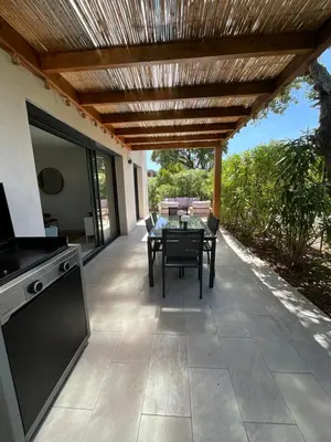 a patio with a table and a wooden pergola at Villa U Sanda in Lecci