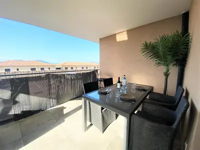 a dining table and chairs on a balcony with a view at Les terrasses de l'Isolella in Porticcio