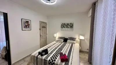 a bedroom with a bed with black and white sheets at chambre d'hôte cosy L'AGHJA in Carbuccia