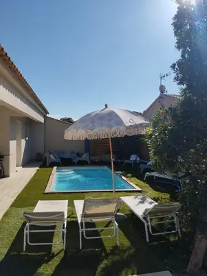 a swimming pool with two chairs and an umbrella at villa Pinarello in Pinarellu