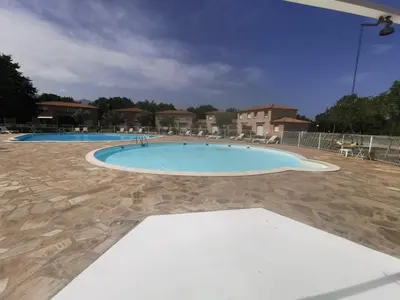 a large swimming pool in a yard with chairs at Villa Melody duplex climatisée piscine in Santa-Maria-Poggio