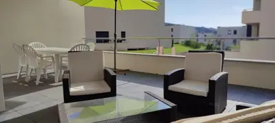 a balcony with a table and chairs and an umbrella at Grand T2 neuf classé 3 étoiles in Porticcio