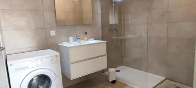 a bathroom with a washing machine and a sink at Grand T2 neuf classé 3 étoiles in Porticcio