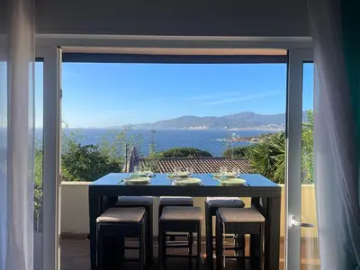 a table with chairs on a balcony with a view of the ocean at Villa Hameaux du soleil in Porticcio