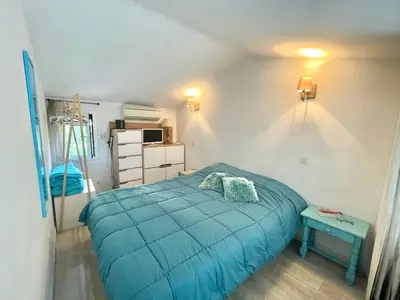 a bedroom with a blue bed and a table at Villa Hameaux du soleil in Porticcio