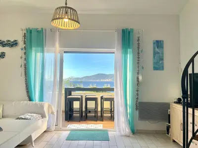 a living room with a table and a view of the ocean at Villa Hameaux du soleil in Porticcio