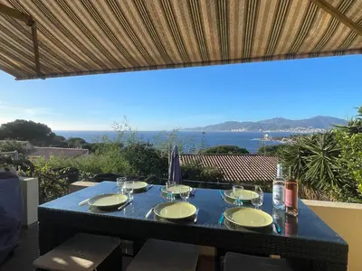 a table with wine glasses on it with a view of the ocean at Villa Hameaux du soleil in Porticcio
