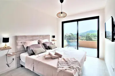 a bedroom with a large bed with a large window at Villa PIETRA 300m de la plage de Favone Piscine privée chauffée in Conca
