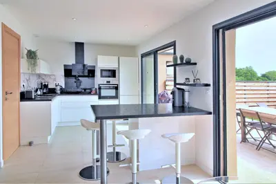 a kitchen with white cabinets and a counter with stools at Villa PIETRA 300m de la plage de Favone Piscine privée chauffée in Conca