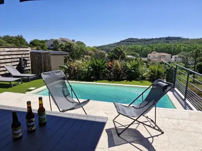 two bottles of wine sitting on a table next to a pool at Villa PIETRA 300m de la plage de Favone Piscine privée chauffée in Conca