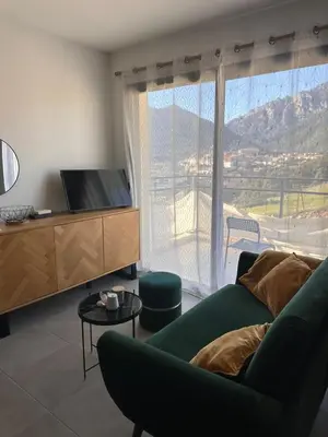 a living room with a couch and a large window at T1 de standing avec vue in Corte