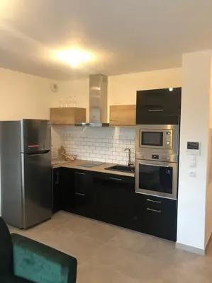 a kitchen with black cabinets and stainless steel appliances at T1 de standing avec vue in Corte