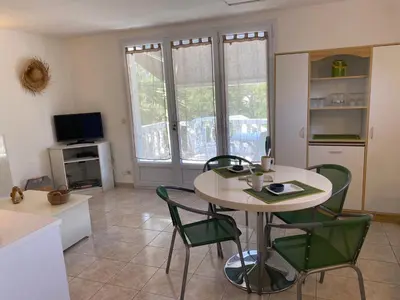 a living room with a table and chairs and a tv at Appartement T2 Olmeto in Olmeto