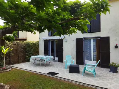 a patio with a table and chairs in front of a house at Agréable villa 100 m de la plage in Poggio-Mezzana