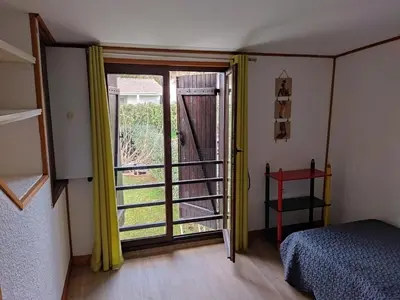 a bedroom with a bed and a window with yellow curtains at Agréable villa 100 m de la plage in Poggio-Mezzana