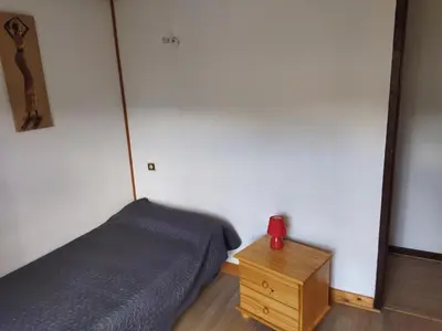 a bedroom with a bed and a red alarm clock at Agréable villa 100 m de la plage in Poggio-Mezzana