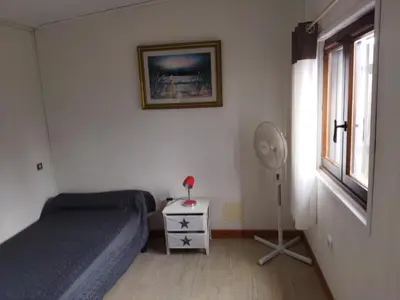 a bedroom with a bed and a fan and a window at Agréable villa 100 m de la plage in Poggio-Mezzana