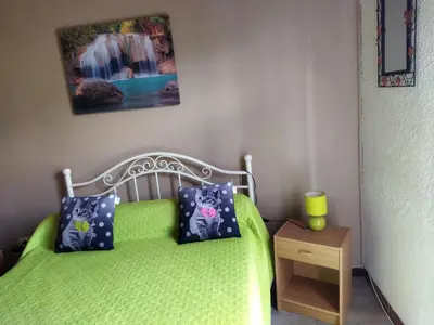 a bedroom with a green bed with pillows and a table at Agréable villa 100 m de la plage in Poggio-Mezzana