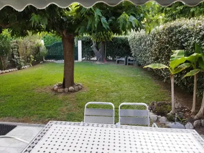 a table and two white chairs in a yard at Agréable villa 100 m de la plage in Poggio-Mezzana