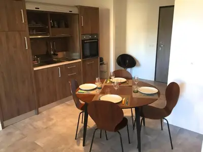 a dining room with a wooden table and chairs at Grand Studio moderne tout confort in Porto-Vecchio