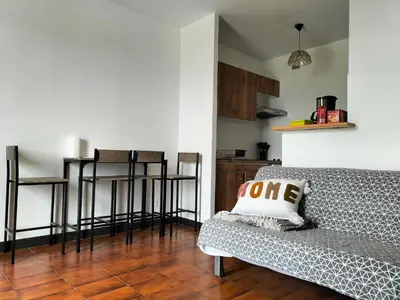 a living room with a couch and some bar stools at Studio face mer Porticcio, proche aéroport Ajaccio in Porticcio
