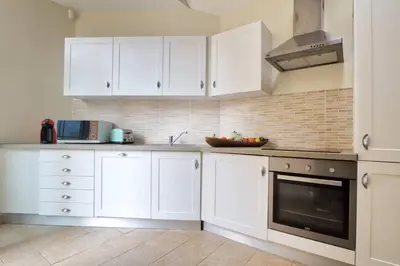a white kitchen with white cabinets and a sink at Le Domaine Saint François Le Moulin 1 in Ajaccio