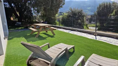 a picnic table and two chairs on a lawn at A LIVIA Peri Ajaccio in Peri