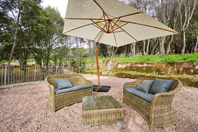 two chairs and a table with an umbrella at Le Domaine Saint François Le Moulin 2 in Ajaccio