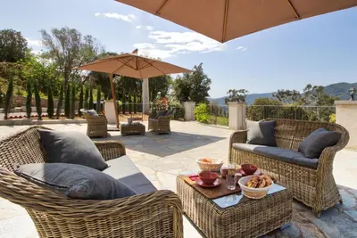 a patio with wicker furniture and an umbrella at Le Domaine Saint François Le Moulin 2 in Ajaccio