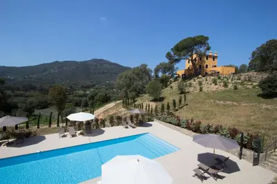 a pool with umbrellas and a house on a hill at Le Domaine Saint François Le Moulin 2 in Ajaccio