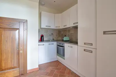 a kitchen with white cabinets and a brown tile floor at Le Domaine Saint François La Tour 1 in Ajaccio