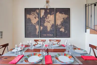 a table with plates and glasses and a map of the world at Le Domaine Saint François la Tour 2 in Ajaccio