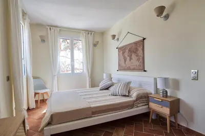 a bedroom with a bed and a table and a window at Le Domaine Saint François la Tour 2 in Ajaccio