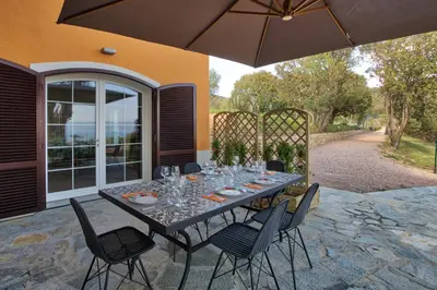 a table with chairs and an umbrella on a patio at Le Domaine Saint François La Tour 3 in Ajaccio