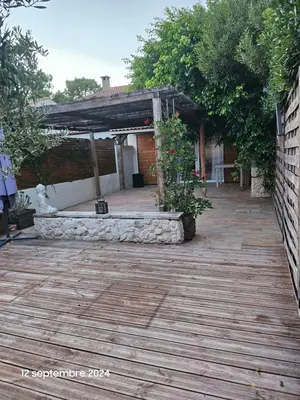 a patio with a wooden floor and a building at Maison Lido Marana plage in Borgo