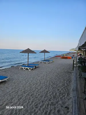 three lounge chairs and umbrellas on a beach at Maison Lido Marana plage in Borgo