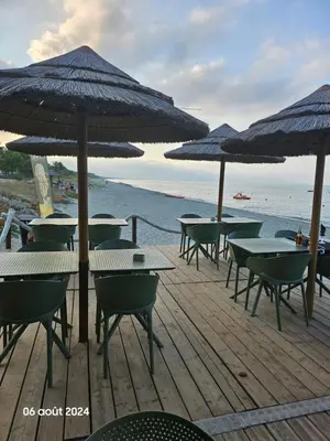 a group of tables and chairs with umbrellas on the beach at Maison Lido Marana plage in Borgo