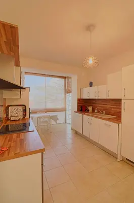 a large kitchen with white cabinets and a table at Appartement centre ville Les Pins Ajaccio in Ajaccio