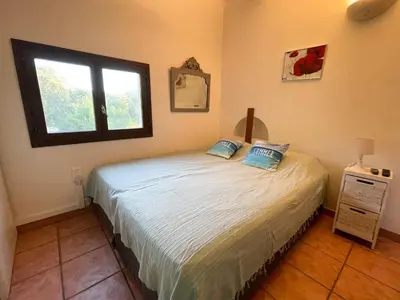 a bedroom with a bed and a window at Maison Asco à Santa Giulia in Porto-Vecchio