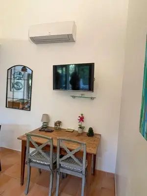 a dining room table with two chairs and a tv on the wall at Maison Asco à Santa Giulia in Porto-Vecchio