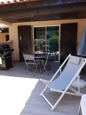 a hammock on a patio with a table and chairs at Villa Occhiatana, Santa Giulia in Porto-Vecchio