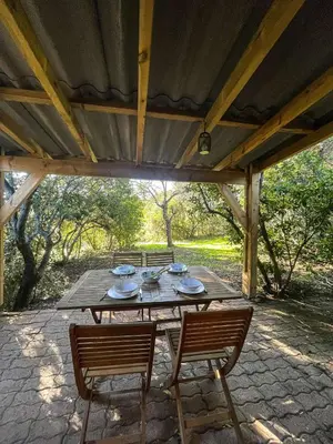 a wooden table with chairs under a wooden roof at Mini villa Centuri, Santa Giulia in Porto-Vecchio