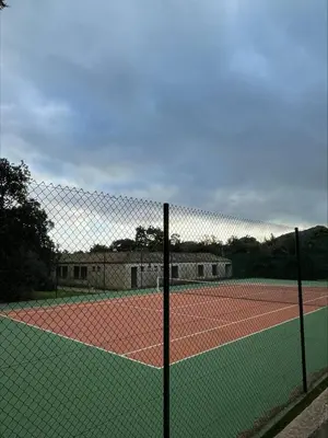 a tennis court with a net on a tennis court at Mini villa Centuri, Santa Giulia in Porto-Vecchio