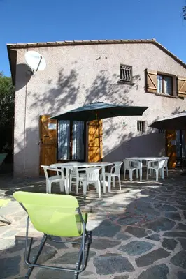 a table and chairs with an umbrella in front of a building at Mini villa Erbalunga, Santa Giulia in Porto-Vecchio