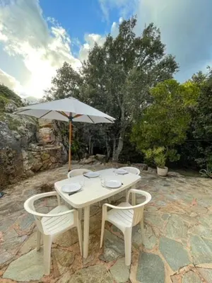 a white table and chairs with an umbrella at Mini villa Erbalunga, Santa Giulia in Porto-Vecchio