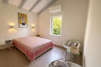 a bedroom with a bed and a window and a chair at Villa San Antonu, Santa Giulia in Porto-Vecchio